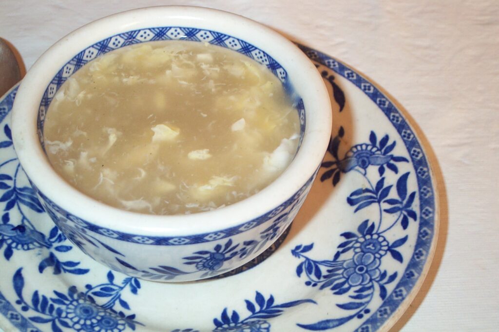 Heiße Keto Egg-Drop-Suppe mit Ei-Fäden in blauer chinesischer Suppenschale