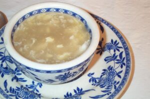 Heiße Keto Egg-Drop-Suppe mit Ei-Fäden in blauer chinesischer Suppenschale