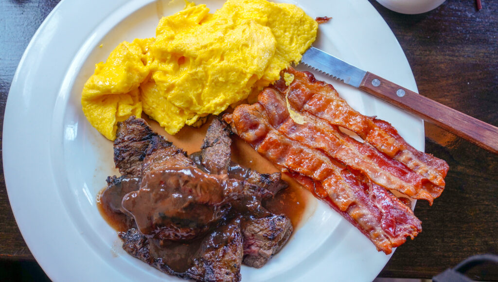 Keto Frühstücksteller mit Steak, Rührei und Bacon auf weißem Teller