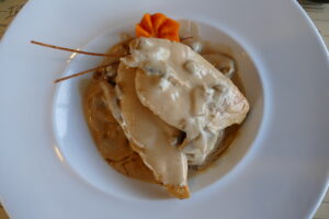 Keto Hähnchenbrust mit cremiger Pilz-Sahnesauce auf weißem Teller