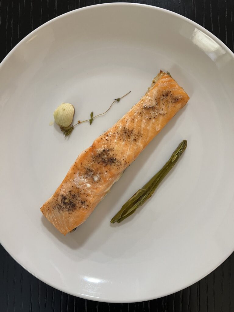 Saftig gegarter Lachs mit Chili und Knoblauch auf weißem Teller